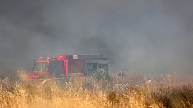 Πυροσβεστικό ελικόπτερο ρίχνει νερό σε φωτιά σε χαμηλή βλάστηση