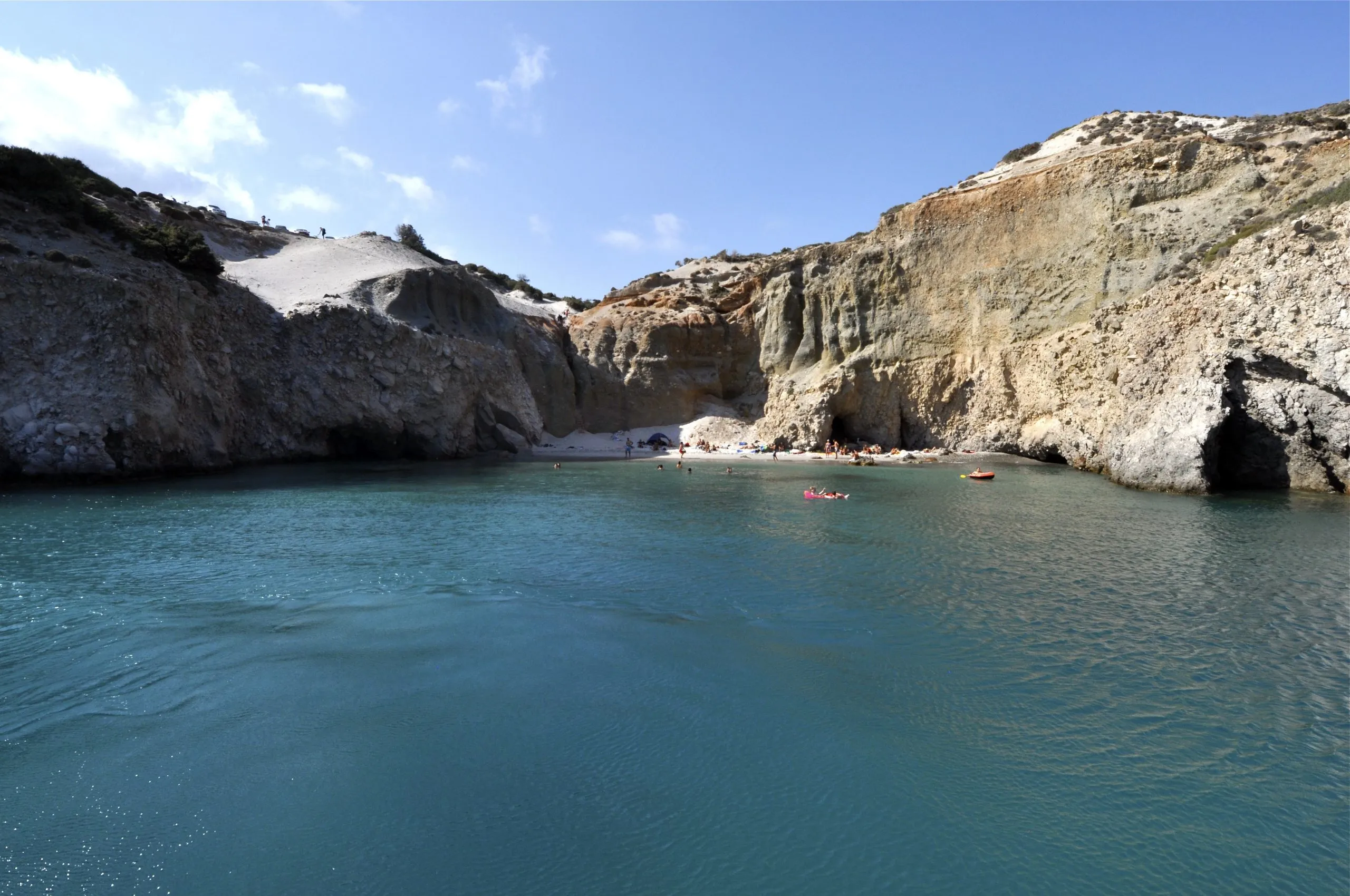 Βραχώδης ακτή στο Κλέφτικο της Μήλου με τουριστικό σκάφος